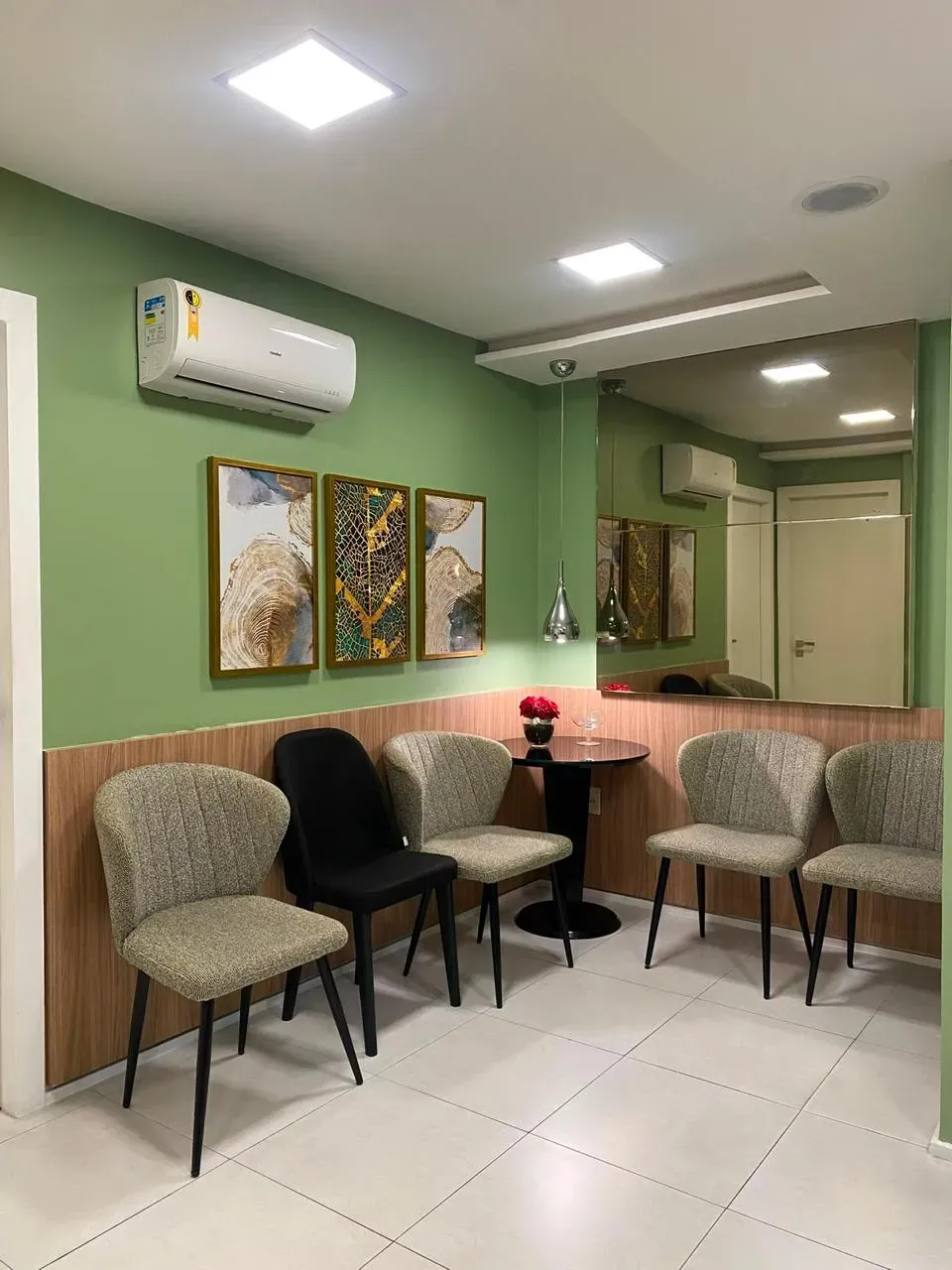 Sala de espera do consultório, com poltronas e quadros na parede verde