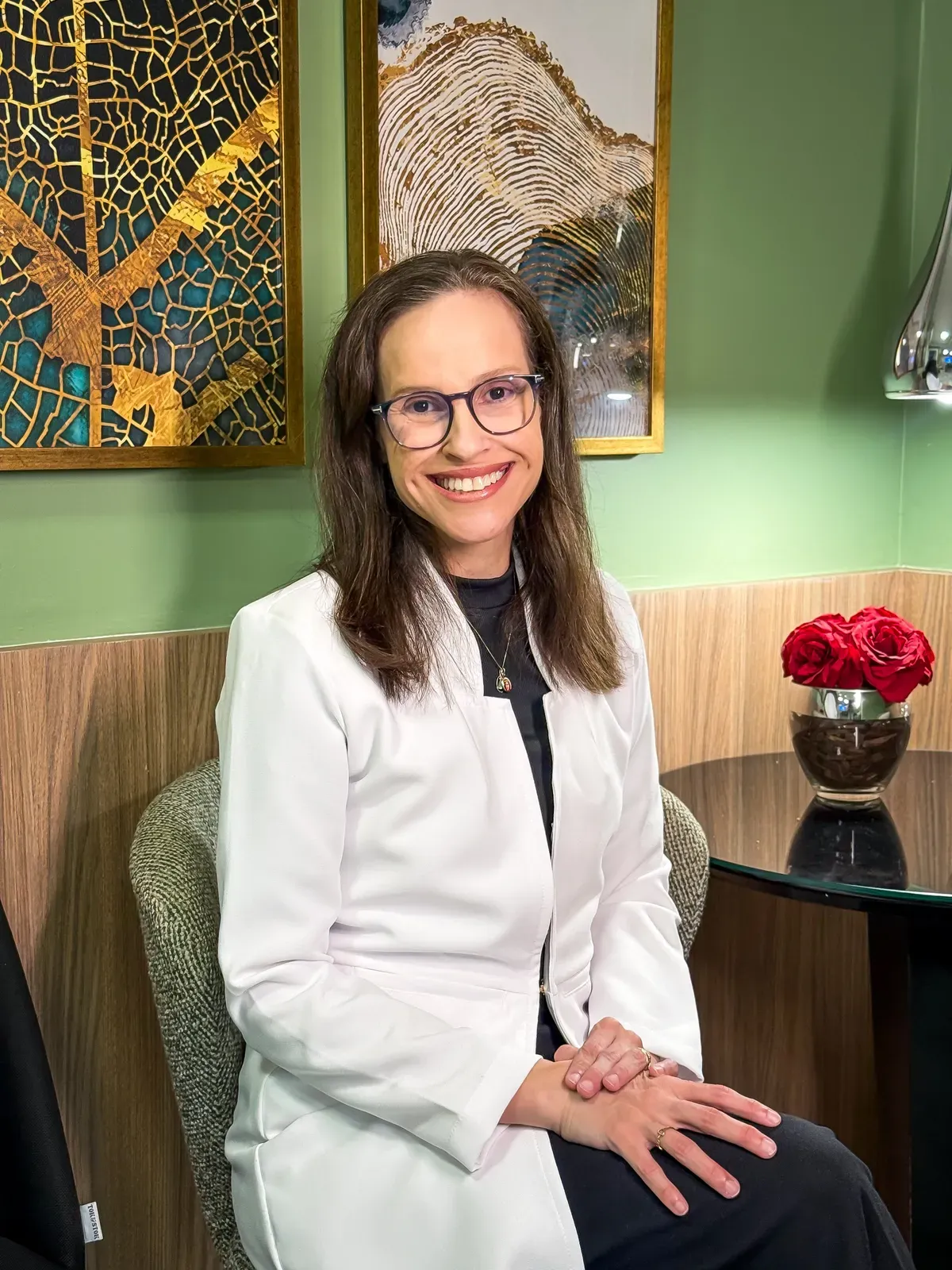 Dra. Lara Santiago de jaleco, sorrindo, na recepção do consultório